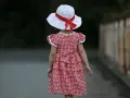 Dziewczynka w sukience w kratkę i kapeluszu z czerwoną wstążką, styl inspirowany modą lat 60.
