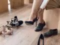 Kobieta przymierza granatowe szpilki. Wokół leżą inne buty, w tym eleganckie oksfordki. Czy 18 cm jaki to rozmiar buta?