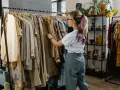 Kobieta przegląda ubrania w sklepie, który wygląda jak **outlet**. Znajduje tam unikatowe perełki.