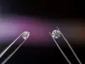 Dwa kamienie szlachetne w pęsecie: surowy brylant i oszlifowany diament.
