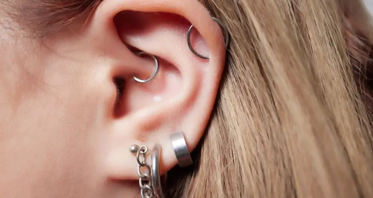Ucho z kilkoma kolczykami, w tym modnym daith piercingiem.