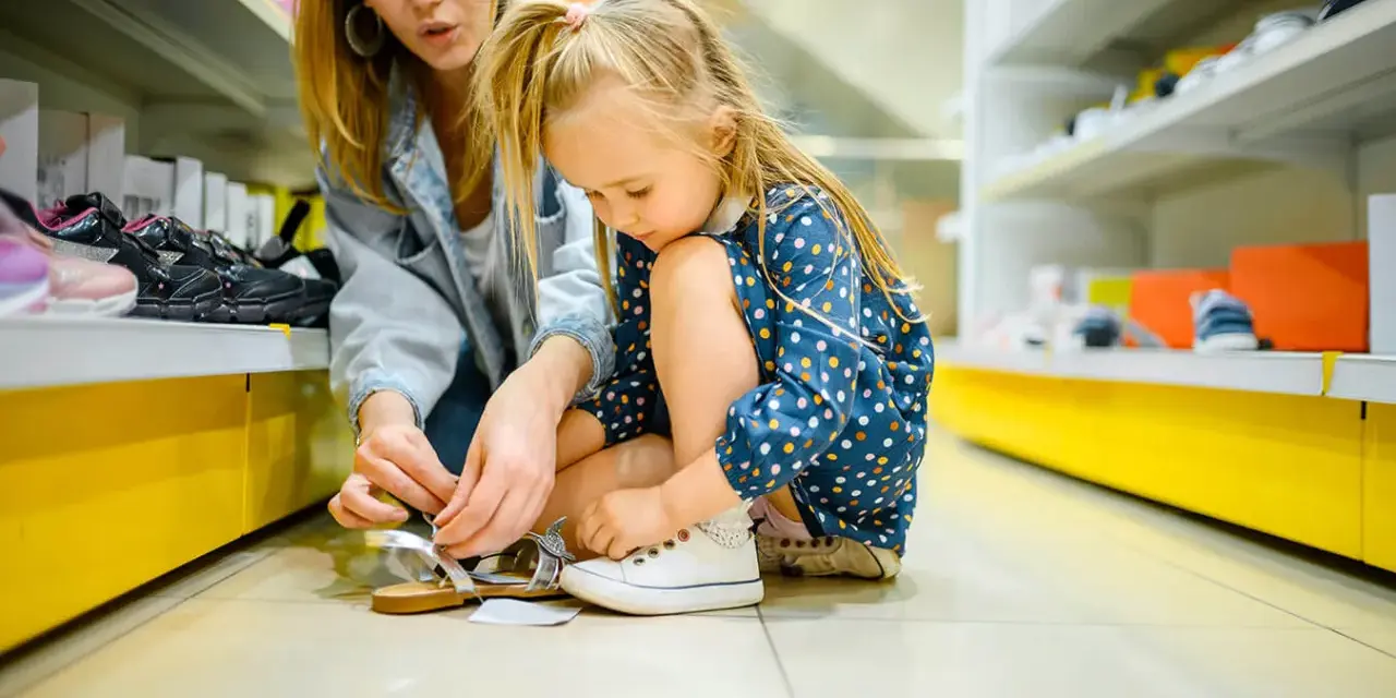 Mama pomaga córce dobrać sandałki, rozmiar 22, idealne dla przedszkolaka.