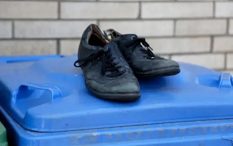 Stare buty na niebieskim koszu na śmieci. Zastanawiasz się, gdzie wyrzucać stare buty? To miejsce może być odpowiedzią.