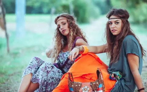 Dwie dziewczyny w stylu boho, idealne inspiracje na imprezę w stylu lat 70 jak się ubrać. Wianki, kwieciste sukienki i kolorowe dodatki.