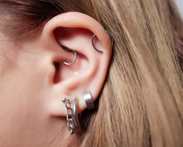 Ucho z kilkoma kolczykami, w tym modnym daith piercingiem.