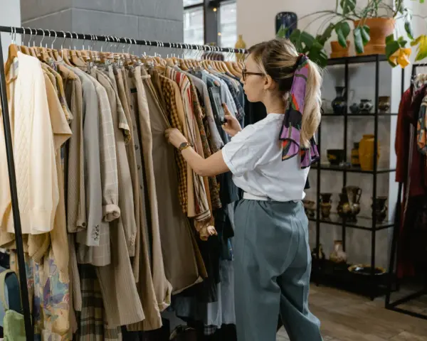 Kobieta przegląda ubrania w sklepie, który wygląda jak **outlet**. Znajduje tam unikatowe perełki.