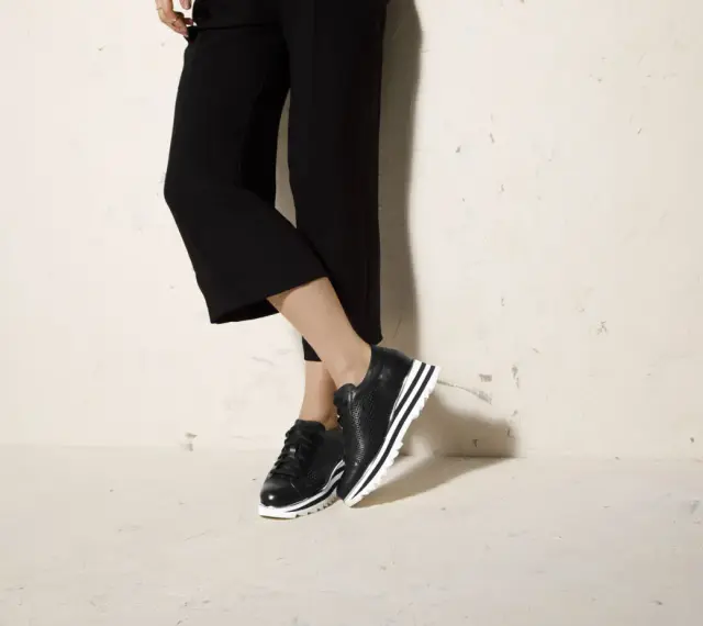 Czarne sneakersy na platformie świetnie komponują się z szerokimi spodniami 3/4, tworząc stylowy look.