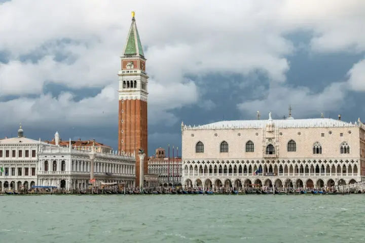Weneckie budowle, w tym Pałac Dożów i Kampanila, na tle burzowych chmur. Venezia to miasto, które zachwyca.
